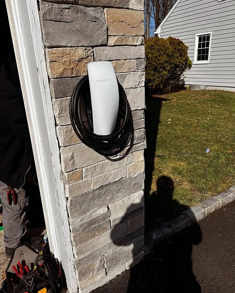 EV charger mounted on a stone pillar next to a driveway