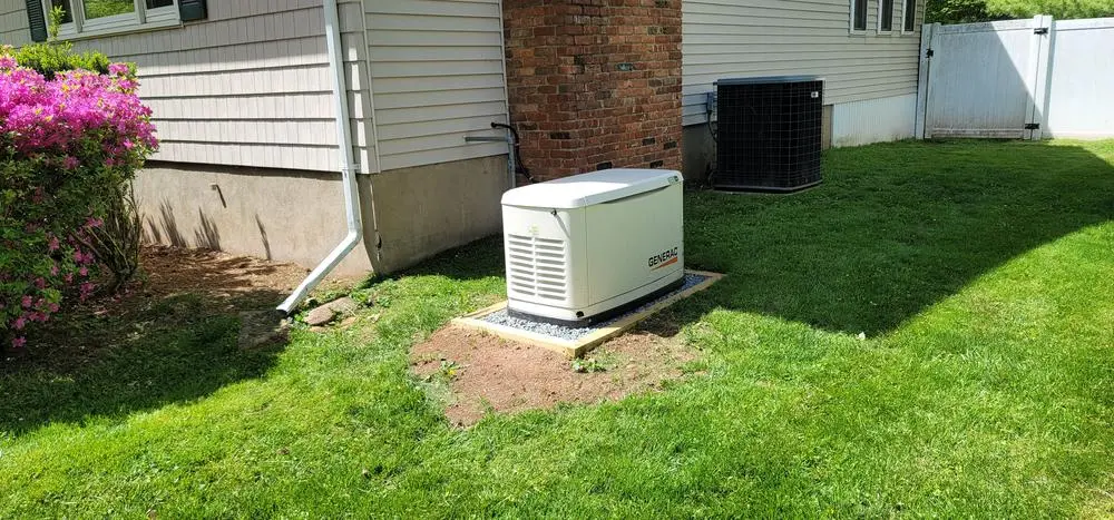 Standby generator on a concrete pad beside a house
